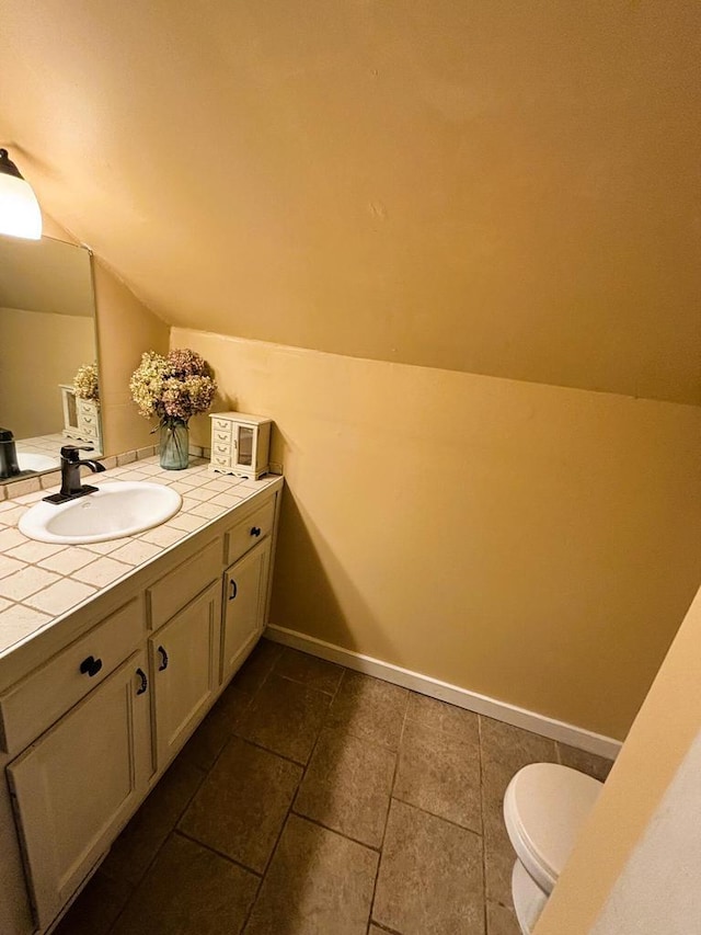 half bath featuring vanity, lofted ceiling, toilet, and baseboards