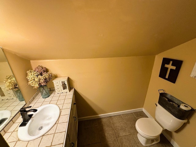 half bath with vanity, lofted ceiling, and baseboards