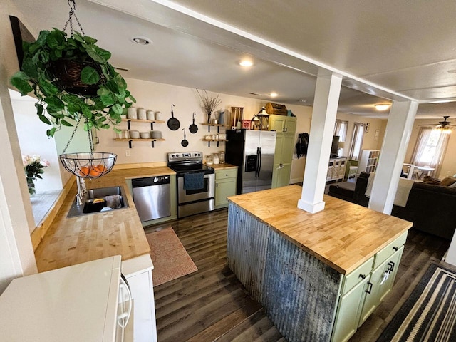 kitchen featuring dark wood-style floors, green cabinetry, a sink, stainless steel appliances, and wood counters