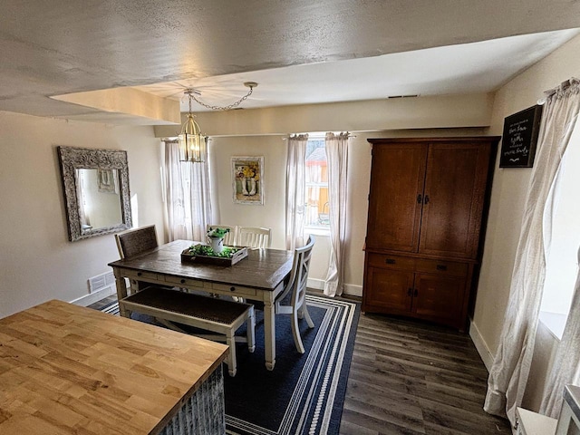 dining room featuring dark wood finished floors, visible vents, an inviting chandelier, and baseboards