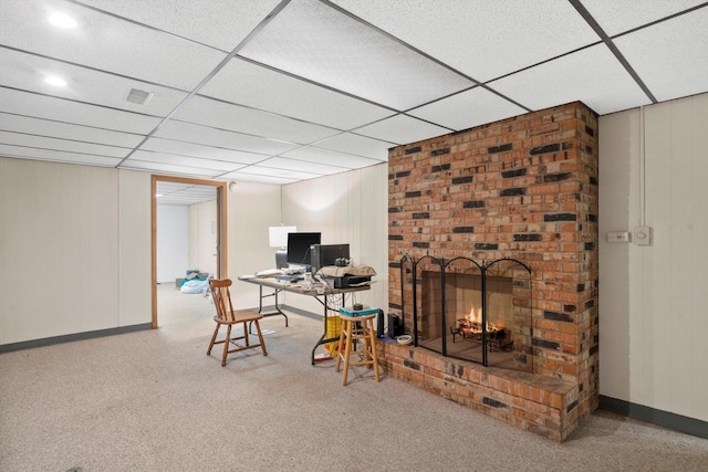 office featuring a brick fireplace, baseboards, visible vents, and a drop ceiling