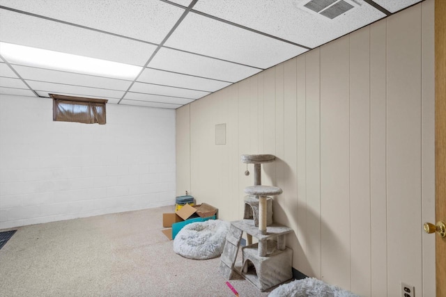 finished basement with visible vents, concrete block wall, and a drop ceiling