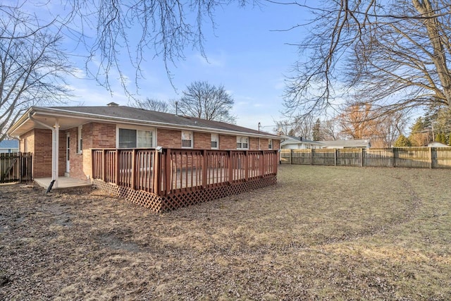 rear view of house featuring a wooden deck, brick siding, and a fenced backyard