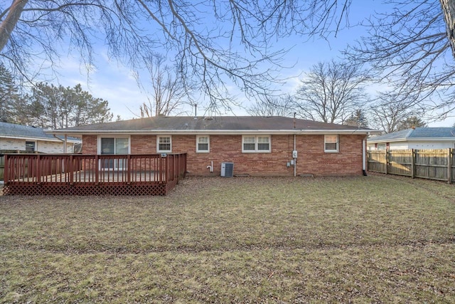 rear view of house with brick siding, a deck, a yard, and a fenced backyard