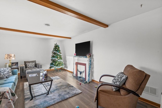 living area with beamed ceiling, baseboards, visible vents, and wood finished floors