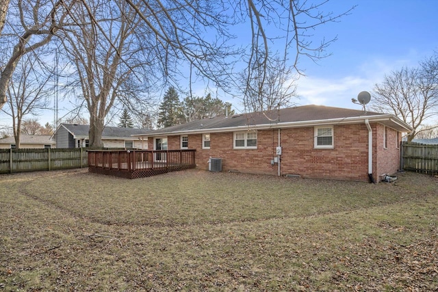 back of house with a yard, a fenced backyard, a deck, central air condition unit, and brick siding