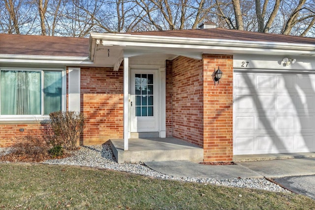 entrance to property featuring a garage, brick siding, and a chimney