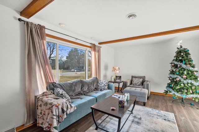 living area with beamed ceiling, baseboards, visible vents, and wood finished floors