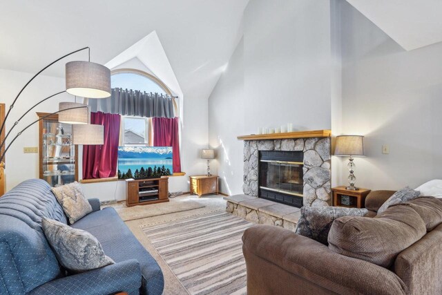 living room featuring a stone fireplace, carpet floors, and high vaulted ceiling