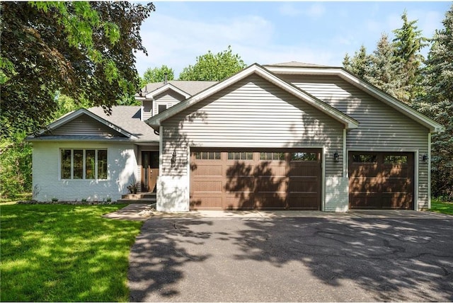 view of front facade with brick siding, aphalt driveway, a garage, and a front yard