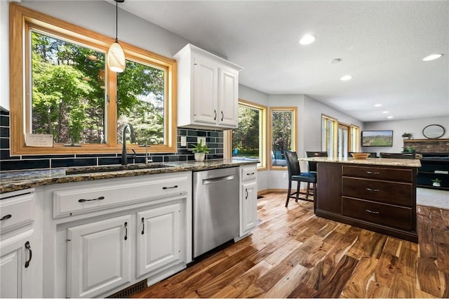 kitchen featuring a sink, backsplash, dark wood finished floors, white cabinets, and dishwasher