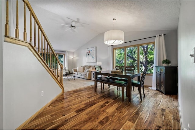 dining room with wood finished floors, baseboards, stairs, vaulted ceiling, and a textured ceiling