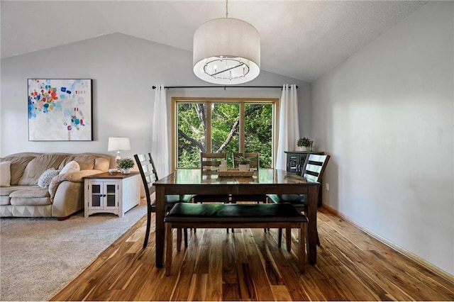 dining area featuring a chandelier, lofted ceiling, and wood finished floors