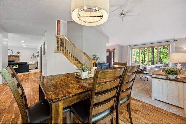 dining room with stairs, a brick fireplace, and wood finished floors