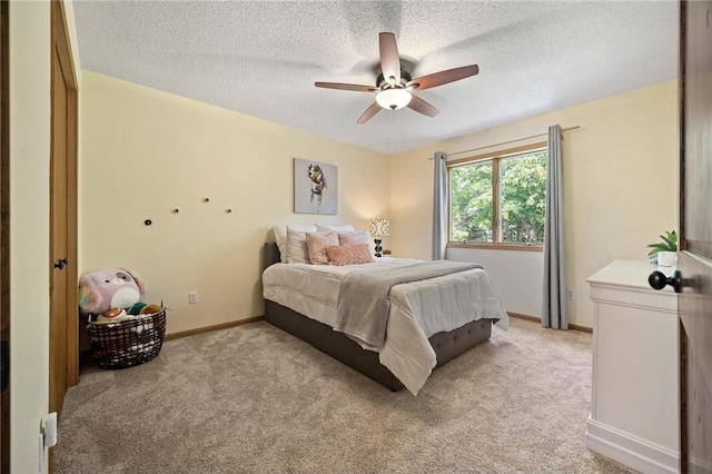 bedroom featuring a ceiling fan, light colored carpet, baseboards, and a textured ceiling