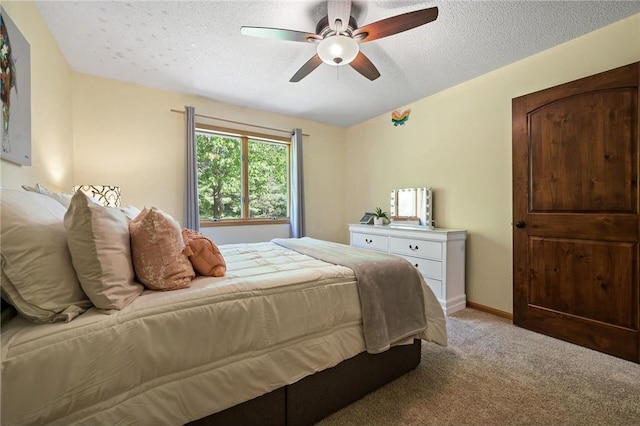 bedroom featuring light carpet, ceiling fan, a textured ceiling, and baseboards