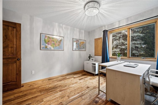 home office featuring a textured ceiling, baseboards, and wood finished floors