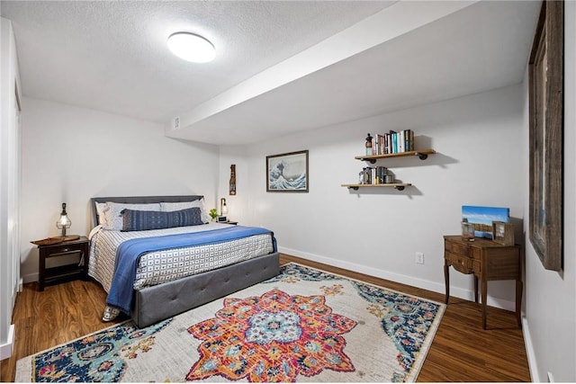 bedroom with a textured ceiling, baseboards, and wood finished floors