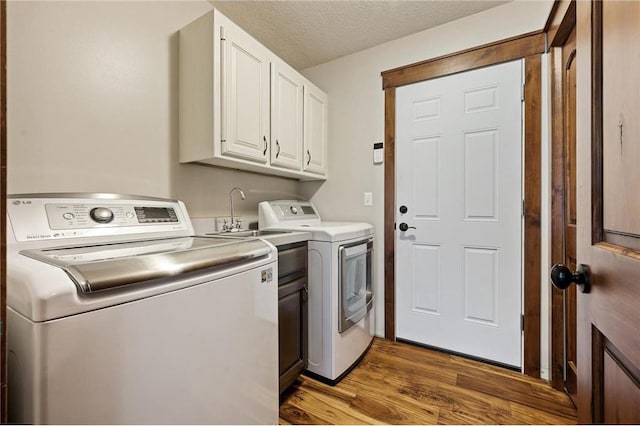 laundry area featuring cabinet space, washing machine and dryer, a textured ceiling, and wood finished floors