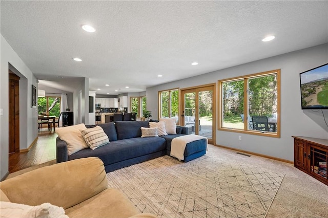 living area with visible vents, plenty of natural light, a textured ceiling, and baseboards