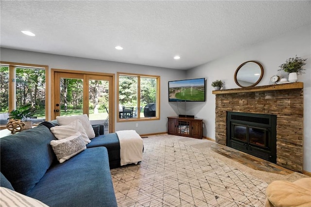 living room with carpet flooring, a textured ceiling, a stone fireplace, and baseboards