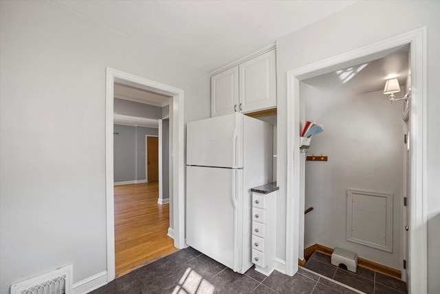 kitchen with visible vents, dark countertops, freestanding refrigerator, white cabinets, and baseboards