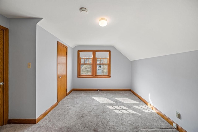 additional living space featuring carpet flooring, baseboards, and vaulted ceiling