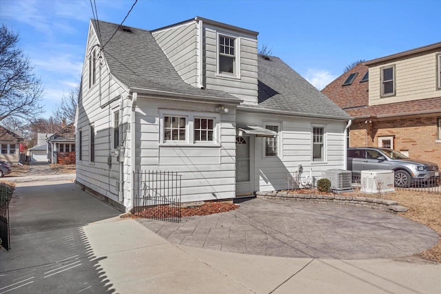 view of front facade featuring roof with shingles, central AC, and concrete driveway