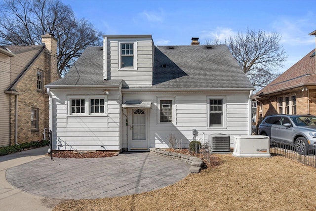 view of front of house with a patio area, central air condition unit, fence, and a shingled roof