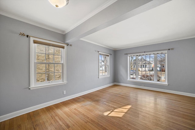 spare room featuring crown molding, baseboards, and wood-type flooring