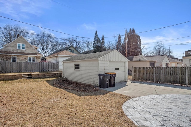 view of side of property featuring an outdoor structure, fence, a garage, and driveway