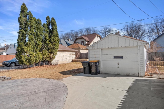 detached garage featuring driveway and fence