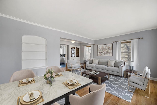 dining room featuring built in shelves, crown molding, baseboards, and hardwood / wood-style flooring