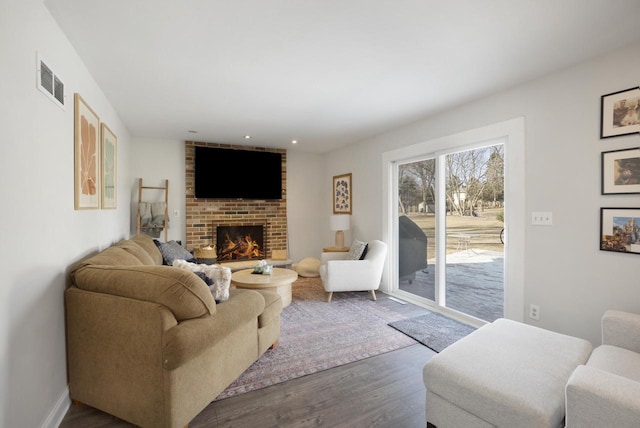 living area with visible vents, recessed lighting, a fireplace, and wood finished floors