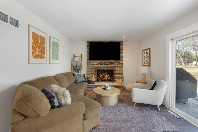 living room with a fireplace, recessed lighting, wood finished floors, and visible vents