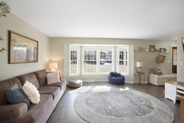 living area with dark wood-type flooring, visible vents, and baseboards