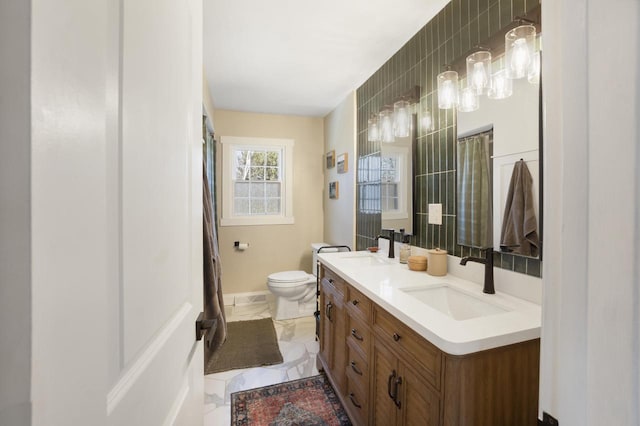 bathroom with double vanity, marble finish floor, toilet, and a sink