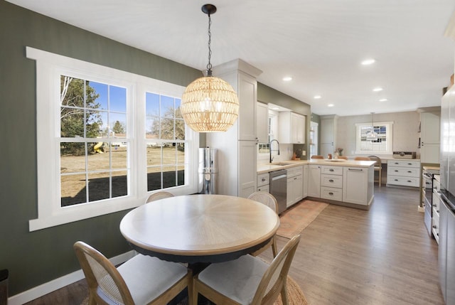 dining room featuring light wood-style flooring, a notable chandelier, recessed lighting, and baseboards