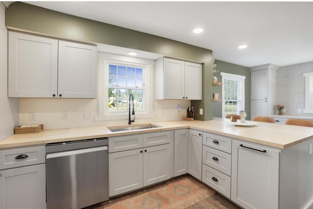 kitchen with light wood-type flooring, a sink, recessed lighting, a peninsula, and dishwasher