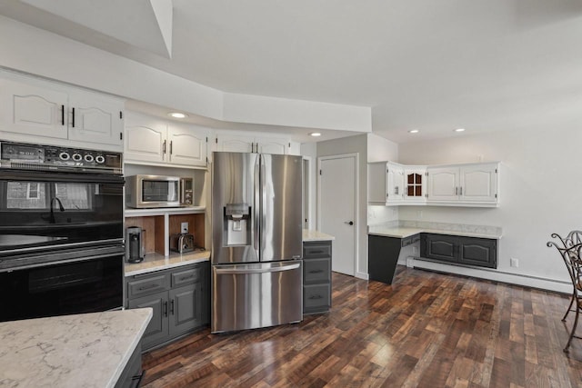 kitchen featuring appliances with stainless steel finishes, white cabinetry, dark wood-type flooring, and a baseboard radiator