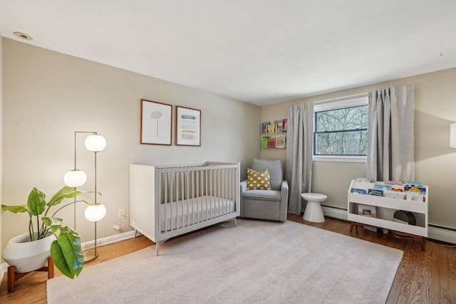 bedroom with a baseboard radiator, baseboards, and wood finished floors