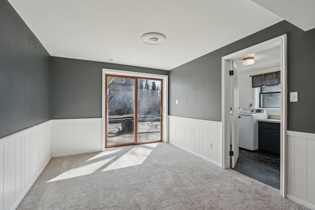 carpeted spare room with a wealth of natural light, washer / dryer, and wainscoting