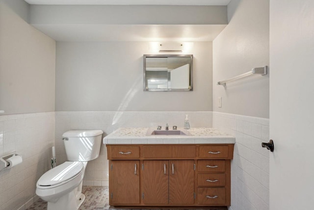 bathroom featuring a wainscoted wall, vanity, toilet, and tile walls