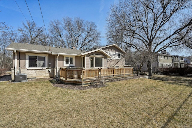 rear view of house featuring a chimney, stone siding, a lawn, and a wooden deck