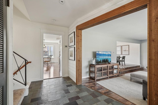 corridor with stairway, baseboards, a notable chandelier, and stone tile floors