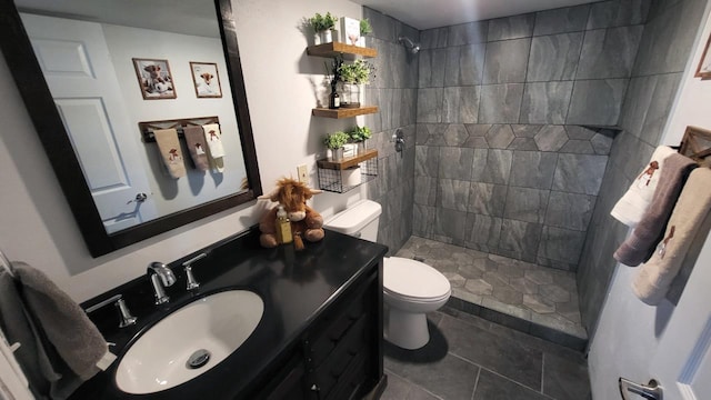 bathroom featuring tile patterned floors, tiled shower, toilet, and vanity