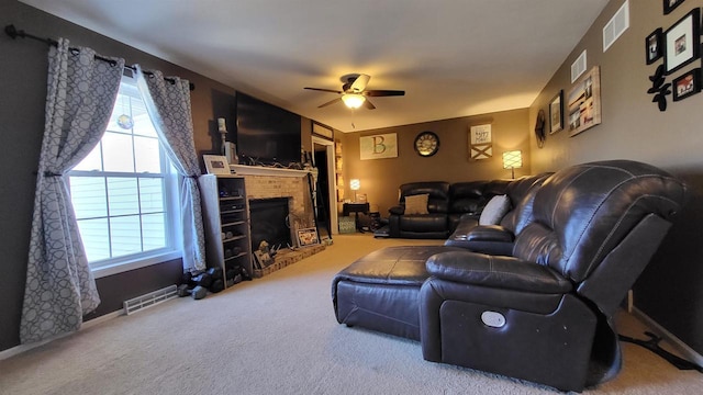 carpeted living room with visible vents, a fireplace, and a ceiling fan