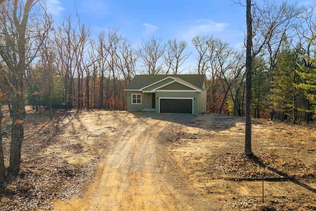 view of front of property featuring an attached garage and dirt driveway