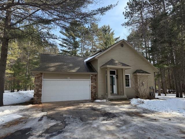 view of front of property featuring a garage, stone siding, and driveway