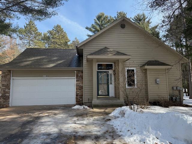 view of front of property featuring concrete driveway, an attached garage, stone siding, and a shingled roof